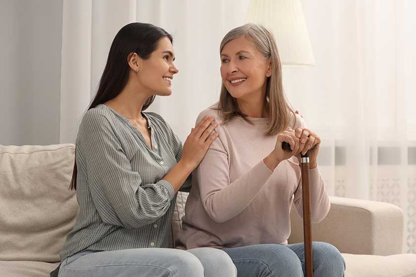 mature-lady-walking-cane-young-woman-sofa-home